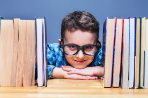 Happy pupil in glasses against books